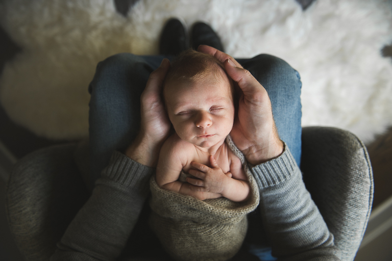 Newborn baby boy being held on Dad's lap portrait