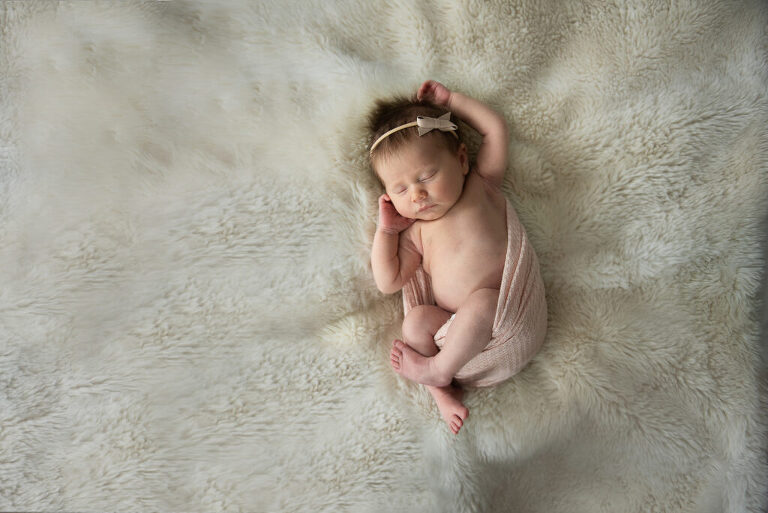 Infant girl in wrap on fur blanket